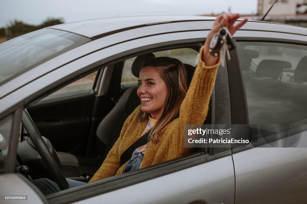 Junge Frau hält Autoschlüssel in einem Auto