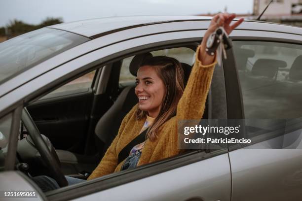 young woman holding car keys inside a car - new imagens e fotografias de stock