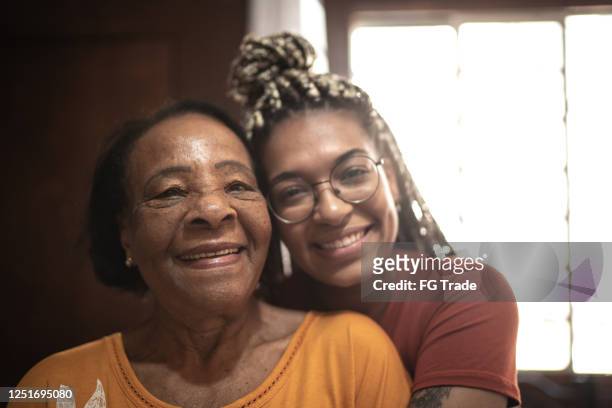porträt von großmutter und enkelin, die sich zu hause umarmen - humility stock-fotos und bilder