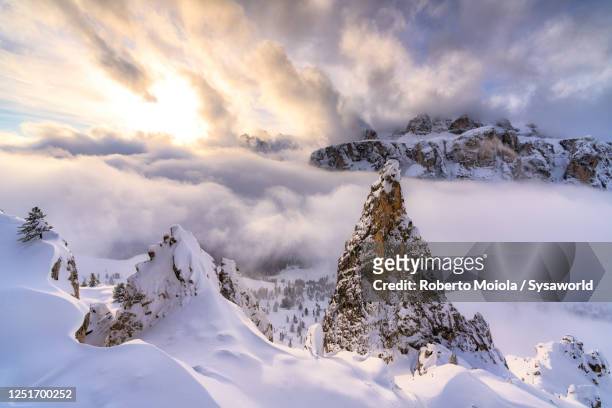 snow covered sella mountain in a sea of clouds, dolomites, italy - gardena stock-fotos und bilder