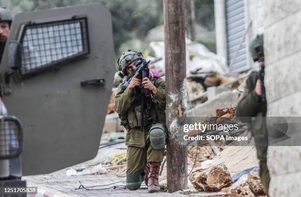 An Israeli soldier aims his weapon at a house, during a military operation, after the Israeli army forces killed Palestinian gunmen, near Elon Moreh,...