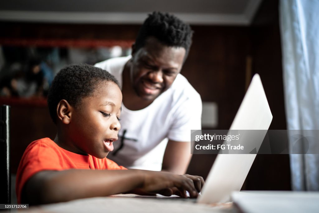 Vater und Sohn studieren mit Laptop auf einem Online-Kurs zu Hause