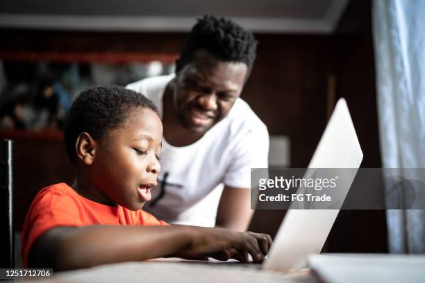 father and son studying with laptop on a online class at home - remote location stock pictures, royalty-free photos & images