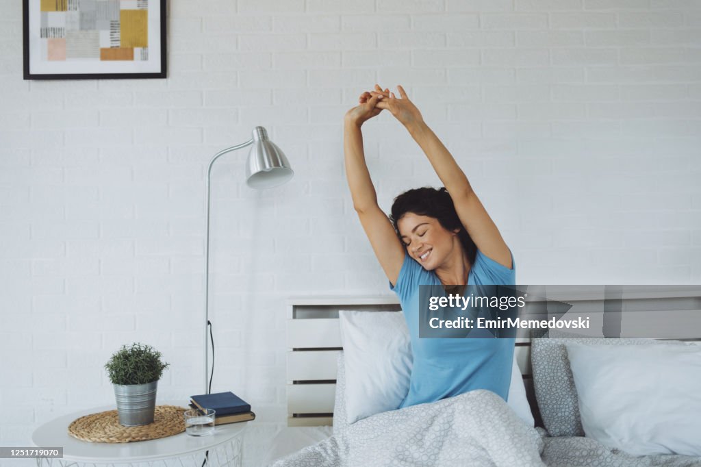 Young Woman Waking Up Rested And Refreshed In Her Bed At Home High-Res ...