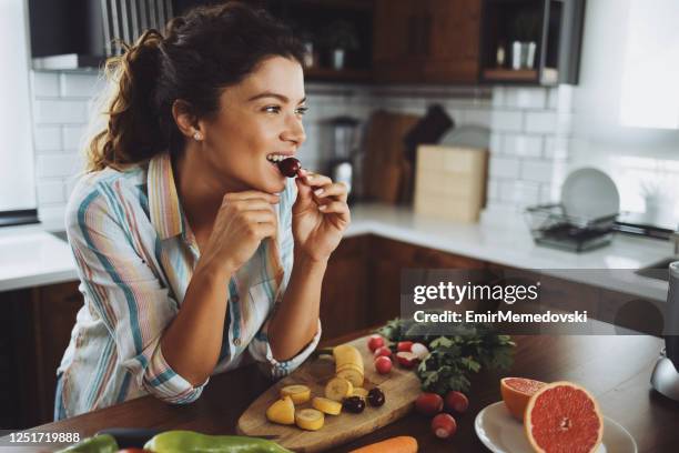 a young smiling woman having healthy breakfast in the morning - woman eating fruit imagens e fotografias de stock