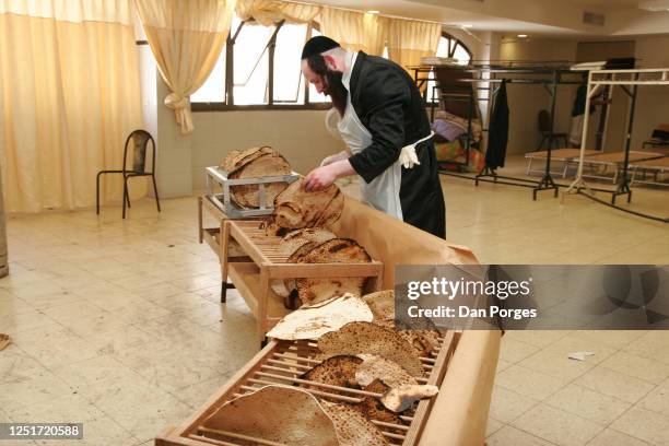 Belz Hasidic man checks the ready matzah shmura once they were taken out of the oven making sure they are neither too hard nor too soft`, he is in a...