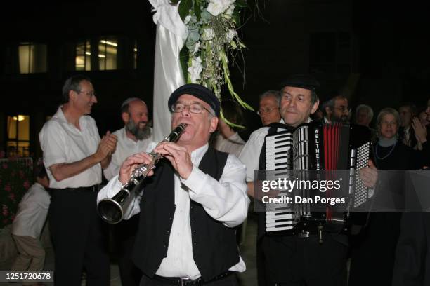 Two klezmers play at dusk in an Orthodox Jewish wedding, one plays the oboe the second plays the accordion, some guests are seen behind, Jerusalem,...