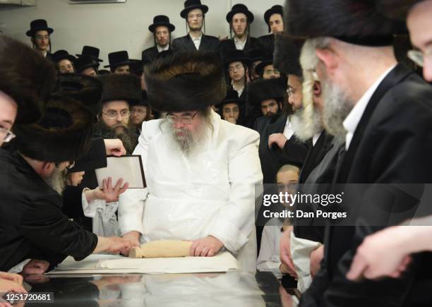 Rabbi Yissachar Dov Rokeach reads a prayer while he cuts kneaded dough into pieces each of which is going to be flattened before it will be baked as...