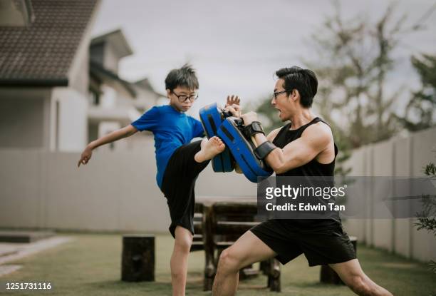 een aziatische chinese vaderatleet die zijn 12 jaar zoon in voortuin van huis in het avond kickboksen op traint - malaysia father and son stockfoto's en -beelden