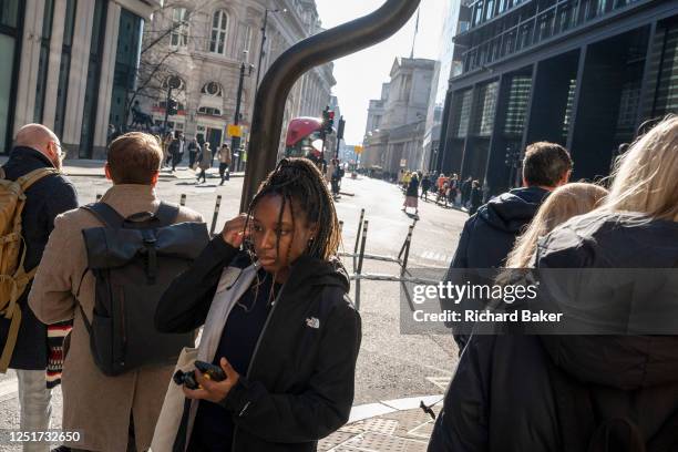 Pedestrians cross the road in front of cycle lane wands in the City of London, aka the Square Mile - the capital's financial district, on 4th April...