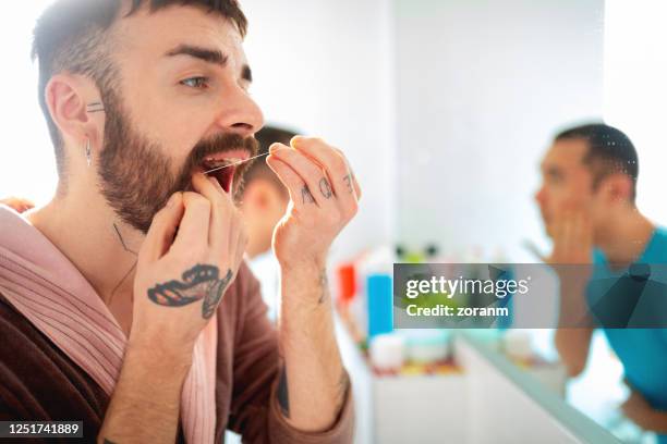 man cleaning teeth with dental floss - tooth bonding stock pictures, royalty-free photos & images