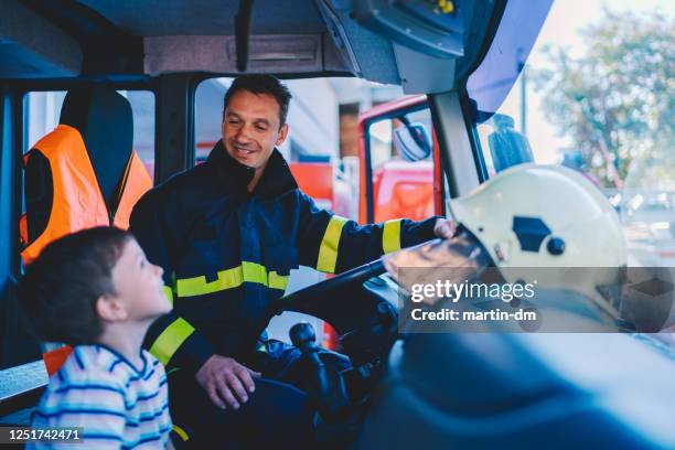 kind träumt davon, feuerwehrmann zu werden - feuerwehr stock-fotos und bilder