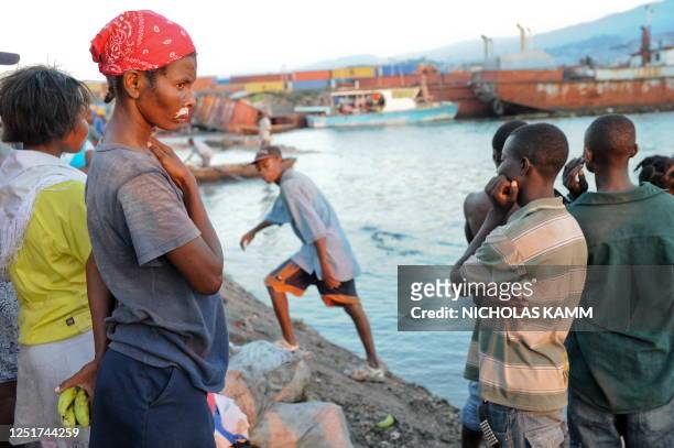 Girl wearing scented cream under her nose to avoid the lingering smell of death watches as the first ferry arrives at the destroyed Jeremie Wharf...