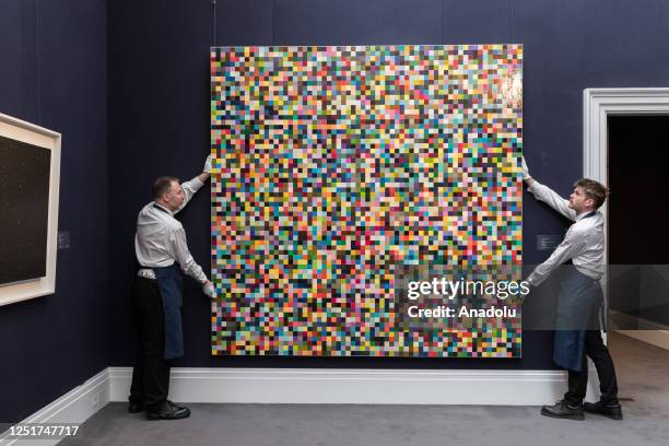 Art handlers hold a painting by Gerhard Richter '4096 Farben' , during a photo call for The New York Sales at Sothebyâs auction house in London,...