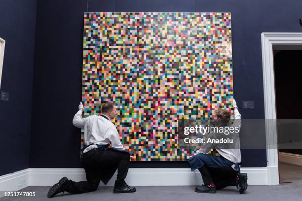 Art handlers hold a painting by Gerhard Richter '4096 Farben' , during a photo call for The New York Sales at Sothebyâs auction house in London,...