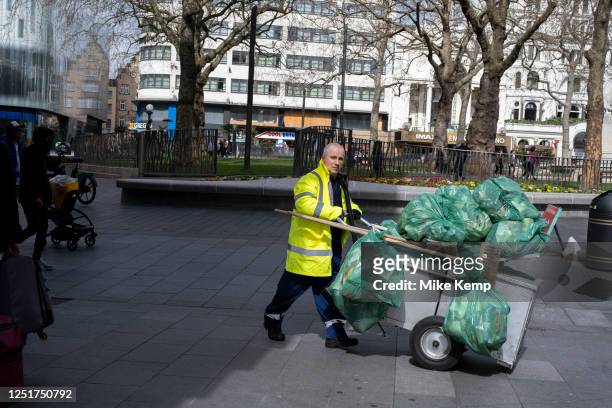 Street sweeper pushes his cart laden with plastic refuse sacks in Leicester Square on 30th March 2023 in London, United Kingdom. Rubbish recycling...