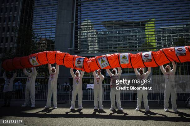 Demonstrators hold up a mock pipeline at a "Stop Fossil Gas" protest outside the World Bank headquarters during the spring meetings of the...