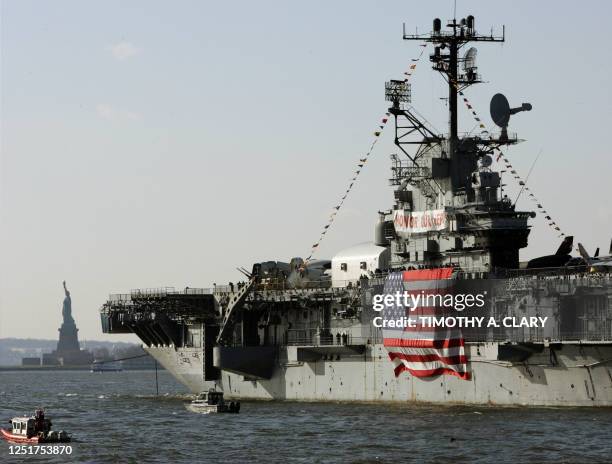 The aircraft carrier USS Intrepid passes the Statue of Liberty as it is towed out of lower Manhattan from its berth at Pier 86 down the Hudson River...