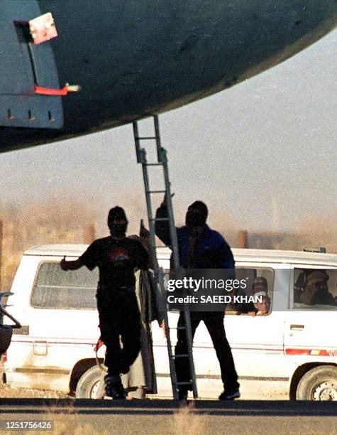 Afghans nationals watch from their van as hijackers flee from an Indian Airlines Airbus after jumping from the cockpit at Kandahar airport in...