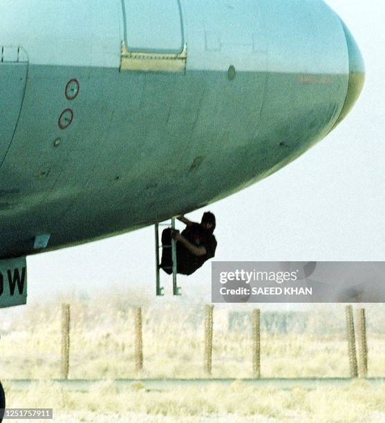 Hijacker holding a pistol climbs down a ladder from beneath the Indian Airlines aircraft cockpit and looks around at the airport in Kandahar,...