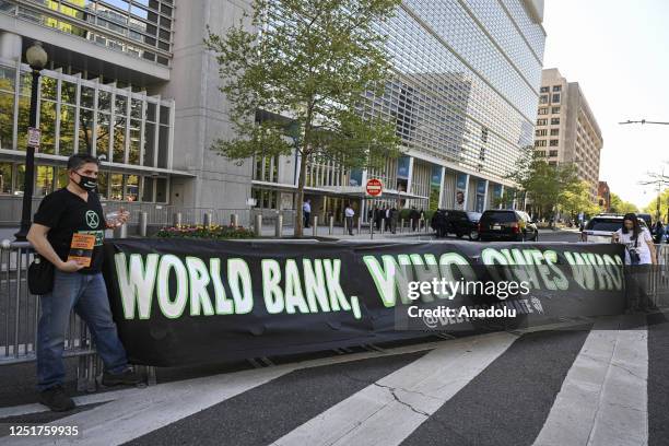 Climate activists open a banner in front of the World Bank during the 2023 Spring Meetings of the International Monetary Fund and the World Bank...