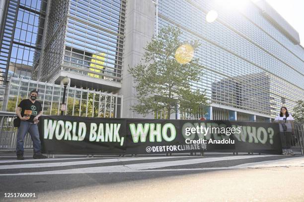 Climate activists open a banner in front of the World Bank during the 2023 Spring Meetings of the International Monetary Fund and the World Bank...