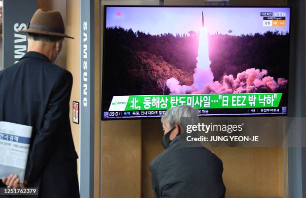 People watch a television screen showing a news broadcast with file footage of a North Korean missile test, at a railway station in Seoul on April...