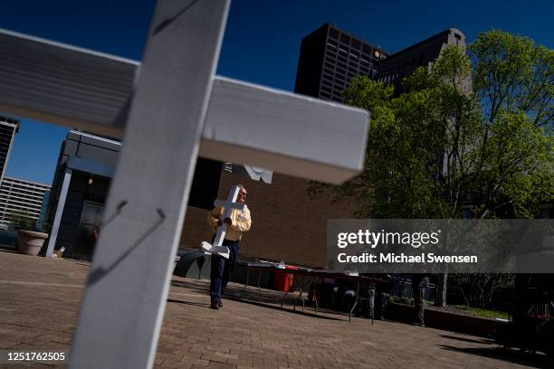 Wayne Kolweier, a member of the Lutheran Church Charities, carries a cross from the memorial at the Old National Bank to the Muhammed Ali Center for...