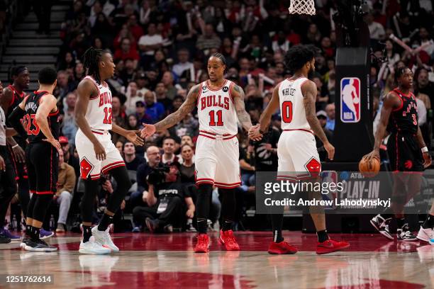 DeMar DeRozan of the Chicago Bulls celebrates with teammates Ayo Dosunmu and Coby White against the Toronto Raptors during the 2023 Play-In...