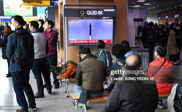 People watch a television screen showing a news broadcast with file footage of a North Korean missile test, at a railway station in Seoul on April...