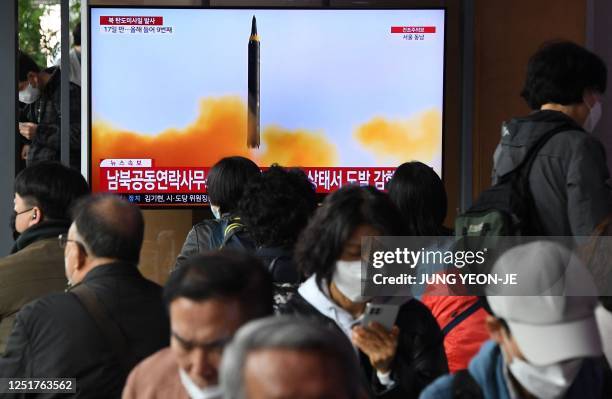 People watch a television screen showing a news broadcast with file footage of a North Korean missile test, at a railway station in Seoul on April...