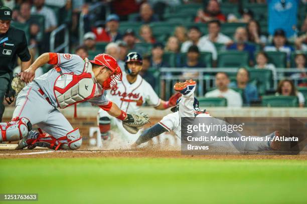 Austin Riley of the Atlanta Braves slides into home avoiding the tag from Luke Maile of the Cincinnati Reds to score a run during the third inning...