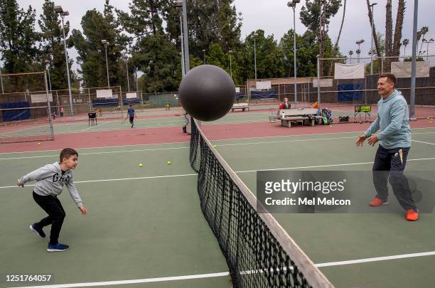 Sam Harutyunyan tosses an exercise ball over the net to tennis instructor Kim Khalimov, while doing a drill to improve forehand and backhand skills...