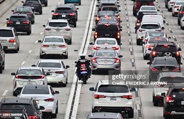 Motorcycle officer weaves through traffic on a Los Angeles freeway during the evening rush hour on April 12, 2023 in Los Angeles, California. - US...