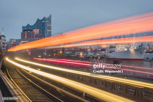 germany, hamburg, train light trails along elevated railway track at dusk - hamburg stock-fotos und bilder