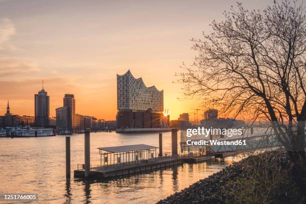 germany, hamburg,empty harbor on bank of elbe river at sunrise withelbphilharmonie in background - elbphilharmonie fotografías e imágenes de stock