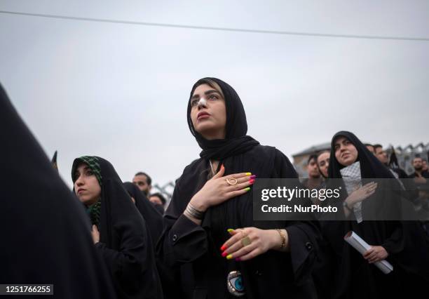 An Iranian woman with colorful artificial nails, beats herself while standing next to veiled women during a religious ceremony in southern Tehran,...