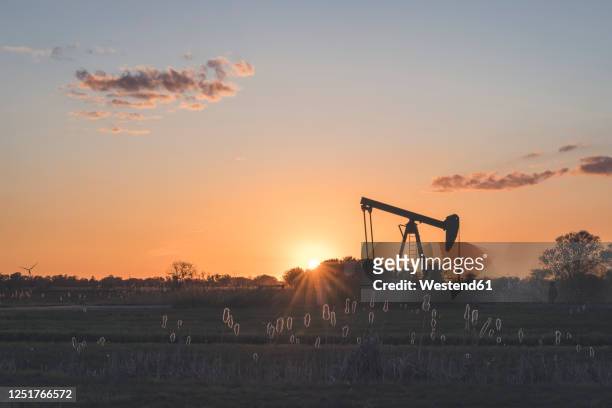 germany, hamburg,silhouette of oil well at sunset - oil field stock-fotos und bilder