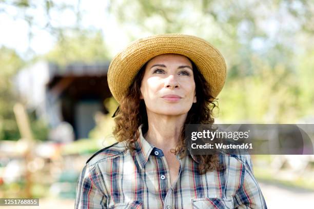 thoughtful mature female farmer looking up while standing at community garden - checked shirt stock pictures, royalty-free photos & images