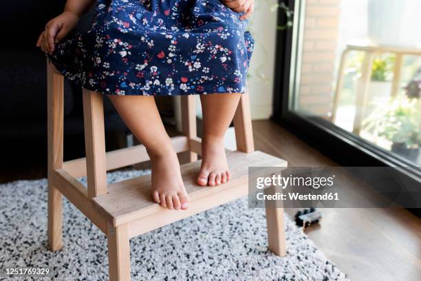 crop view of little girl sitting barefoot on wooden step ladder - step stool stock pictures, royalty-free photos & images