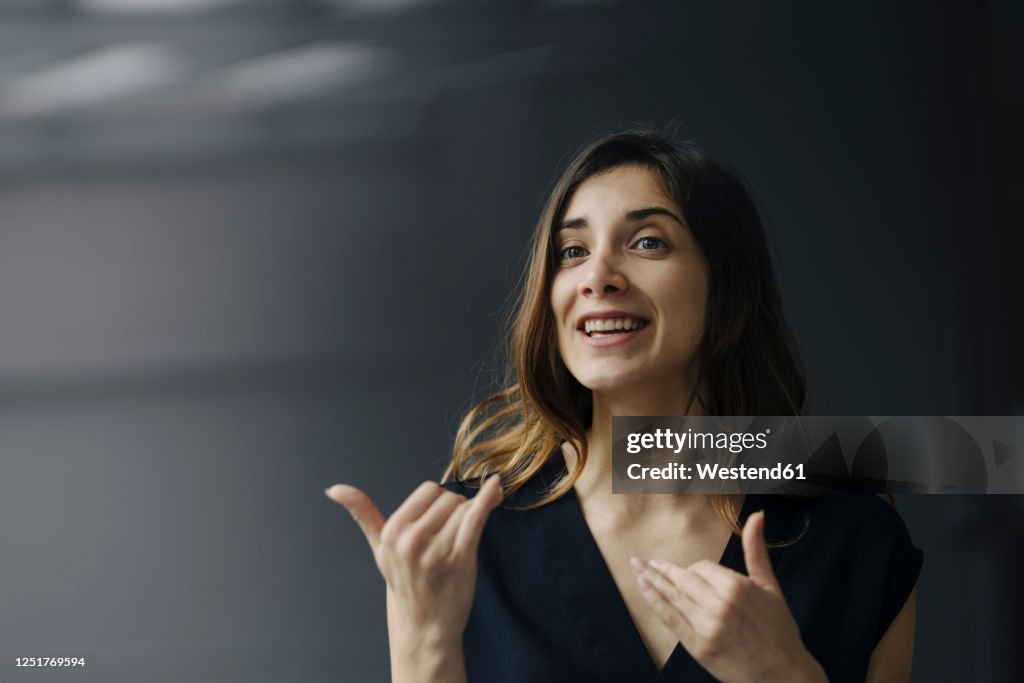 Portrait of gesturing young businesswoman against grey background