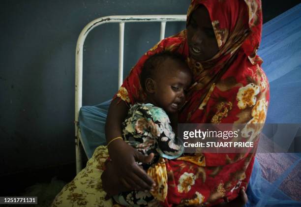 In a photograph released by the African Union-United Nations Information Support Team on August 10 a mother cradles her malnourished and dehydrated...