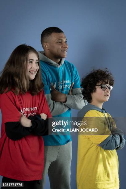 Paris Saint-Germain's and France's International football team French forward Kylian Mbappe poses with children after a football match with the...