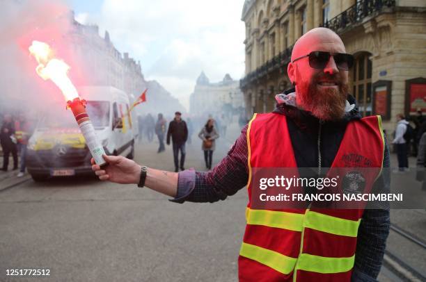 Demonstrator with a vest of the French General Confederation of Labour trade union holds a lighten flare during a demonstration on the 12th day of...