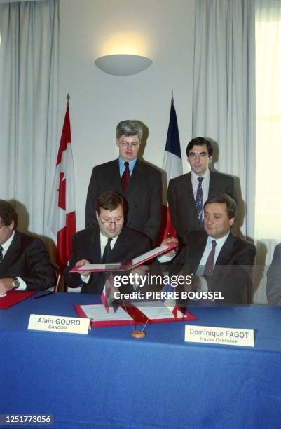 Alain Gourd du CANCOM et Dominique Fagot de Havas Overseas échangent les documents le 23 janvier 1997 à Paris, sous le regard du ministre canadien de...