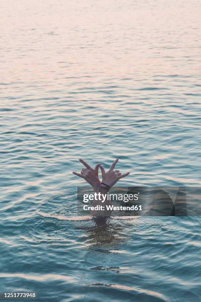 hands of teenage girl diving in the sea showing rock and roll sign - horn sign stock pictures, royalty-free photos & images