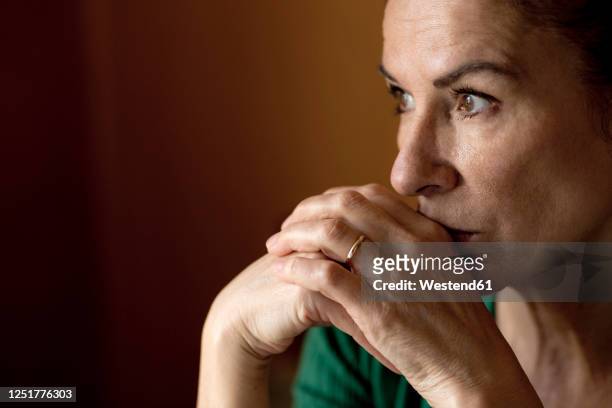 thoughtful lonely mature woman looking away at home during curfew - hand on head stockfoto's en -beelden