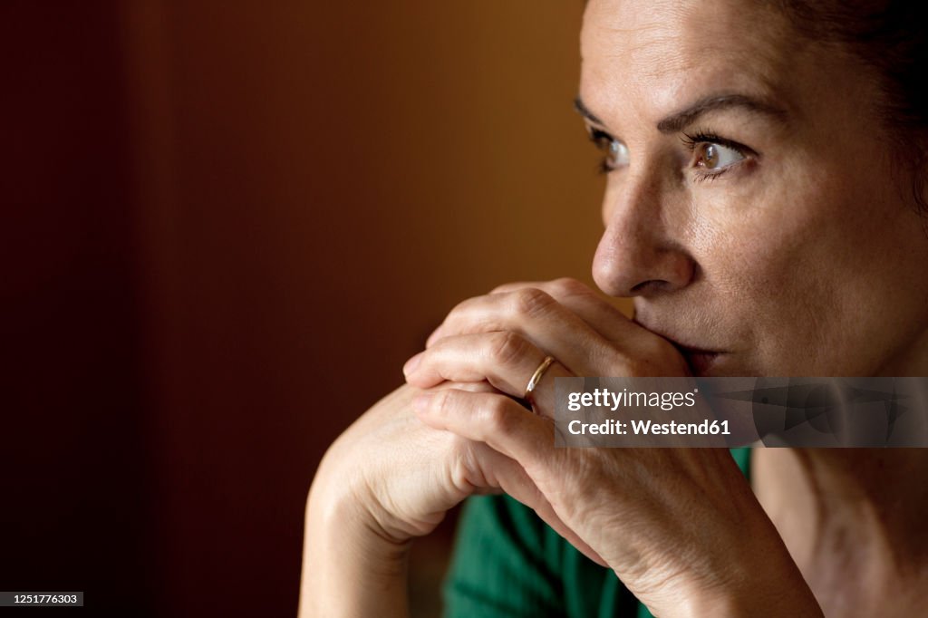 Thoughtful lonely mature woman looking away at home during curfew
