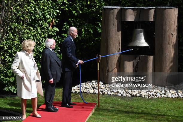 President Joe Biden rings the Peace Bell as Ireland's President Michael D Higgins and his wife Sabina stand by, in the gardens at Aras an Uachtarain...