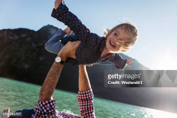 happy girl with arms outstretched being carried by father at achensee, tyrol state, austria - lagos state fotografías e imágenes de stock
